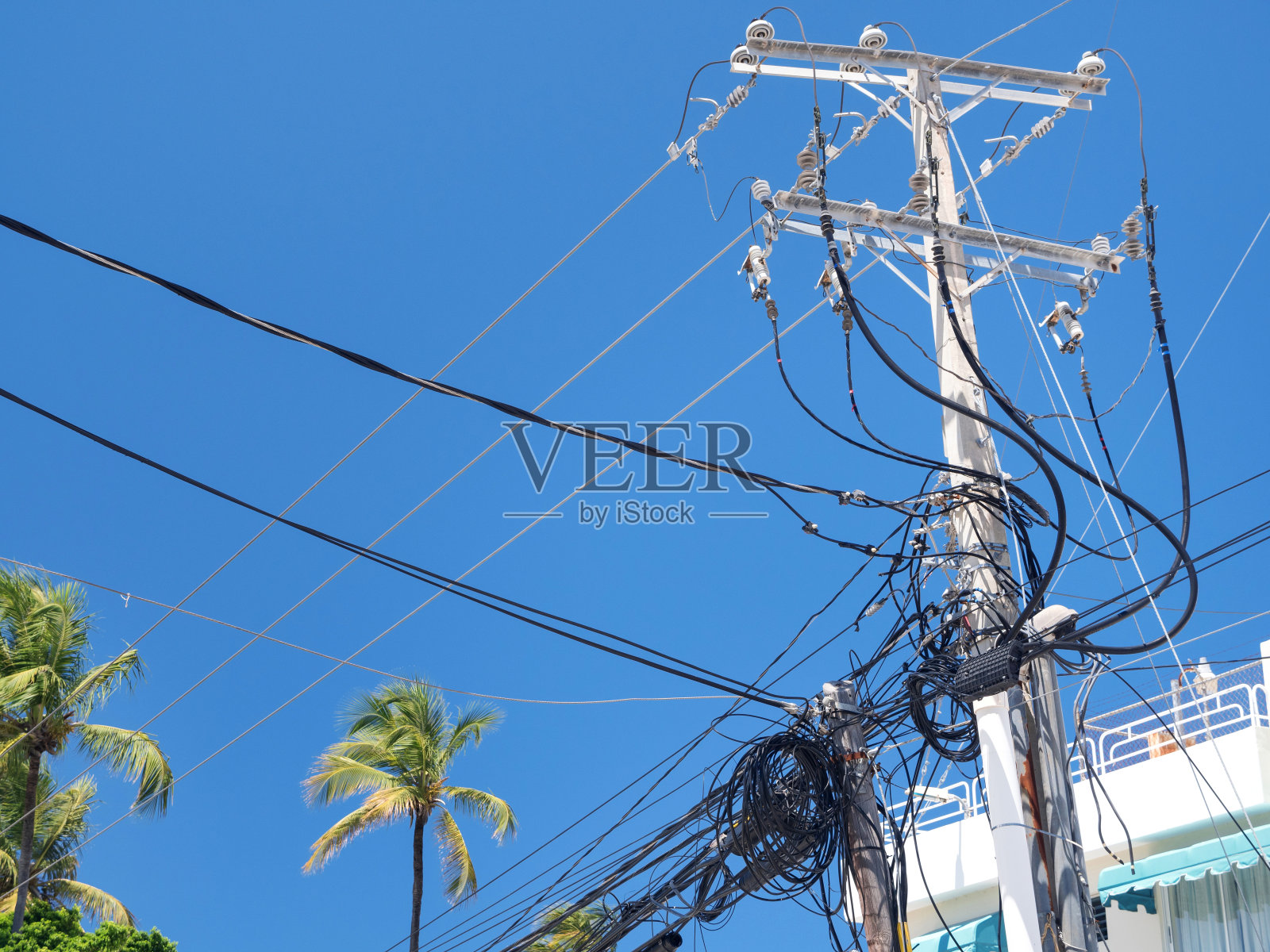 在蓝天背景下,电缆和电线杂乱的电力塔照片摄影图片