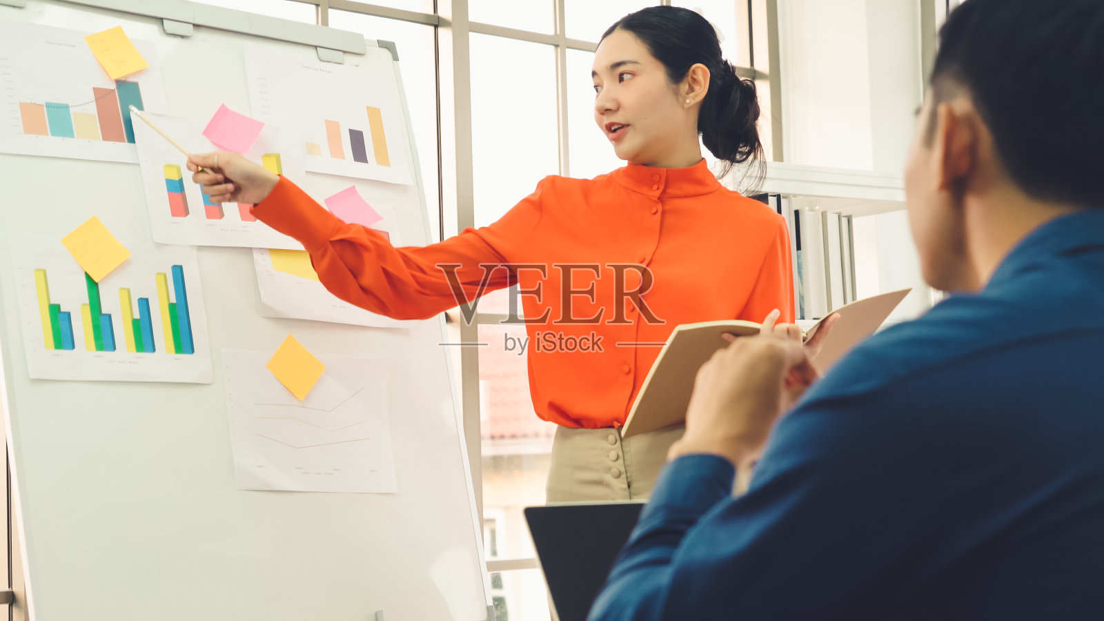 年轻女子在白板上解释商业数据照片摄影图片