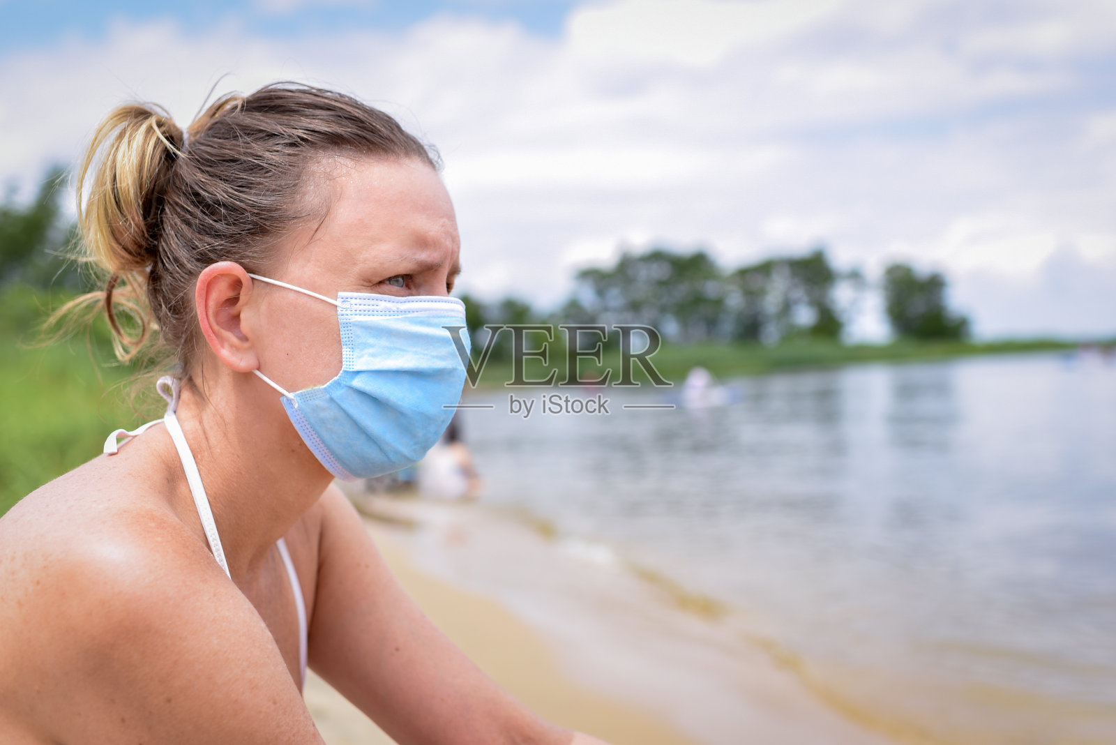 在海滩上戴口罩的年轻女性——2019冠状病毒病夏季照片摄影图片