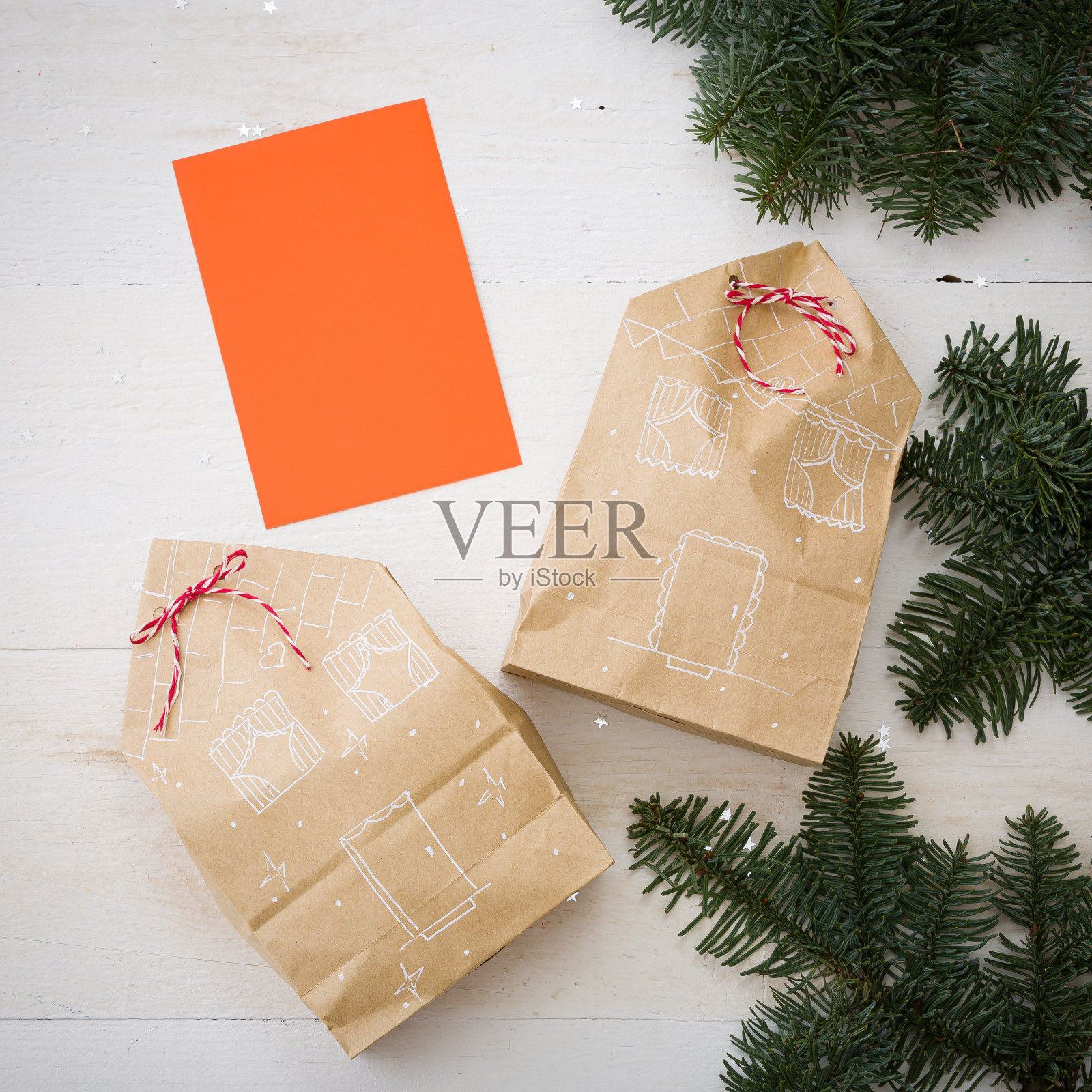 圣诞或新年礼物的特写放在一张白色的木制桌子上。包装好的礼物和有风格的房子。节日和圣诞节概念照片摄影图片