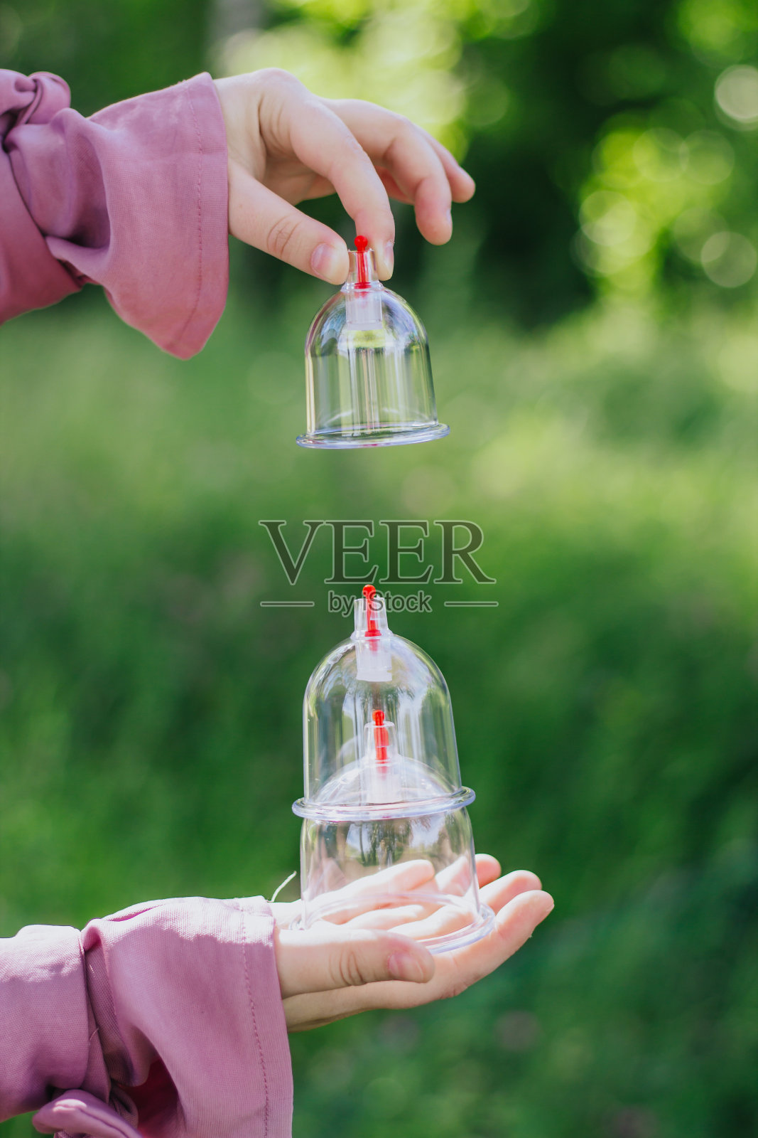 这个女孩拿着一个罐子准备睡觉。Hijama,放血,治疗sunna。在树木和绿色植物的背景下放血用的罐子。照片摄影图片