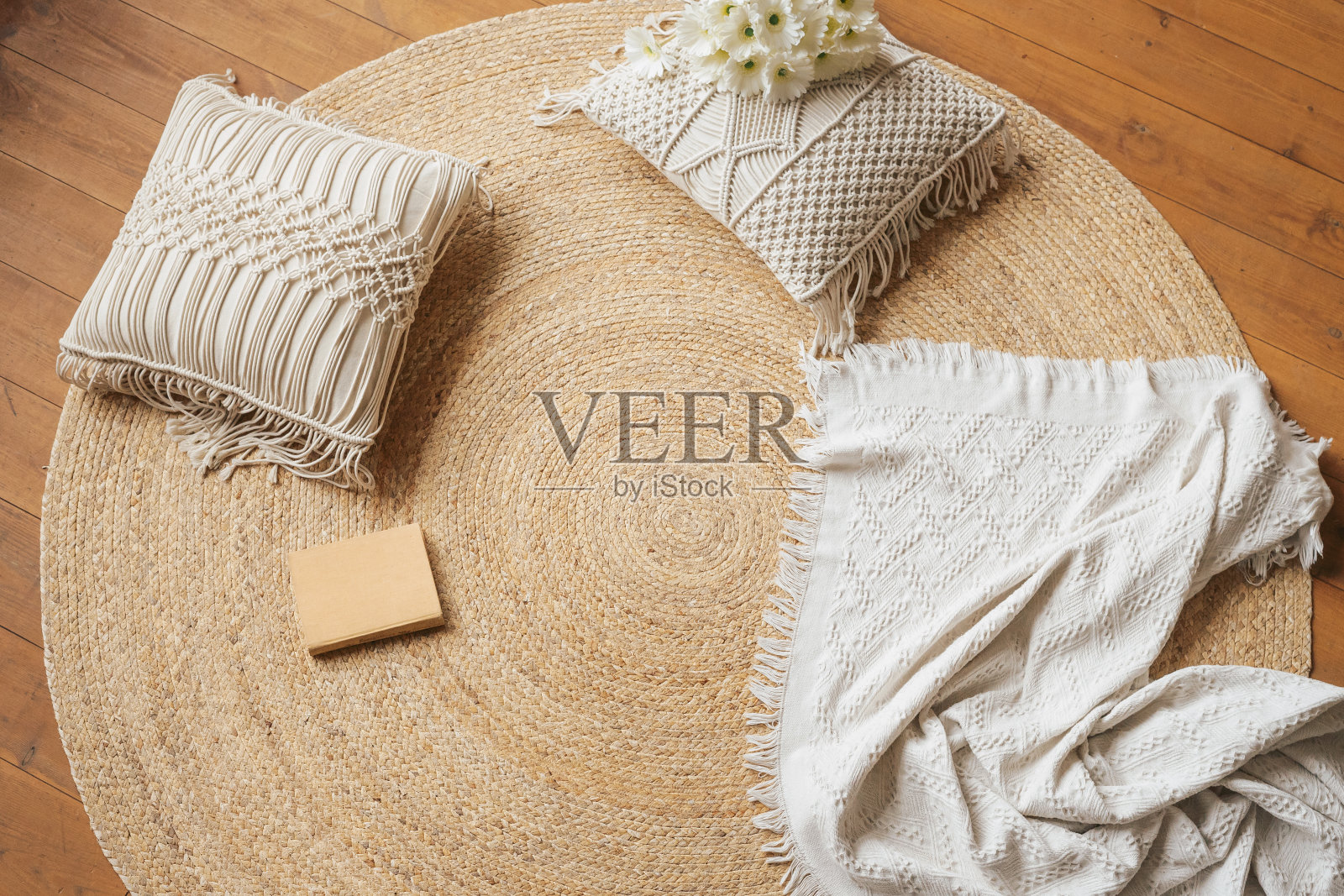 一个躺在地板上看书的舒适地方。黄麻编织圆地毯,macramé枕头,格子和书。照片摄影图片