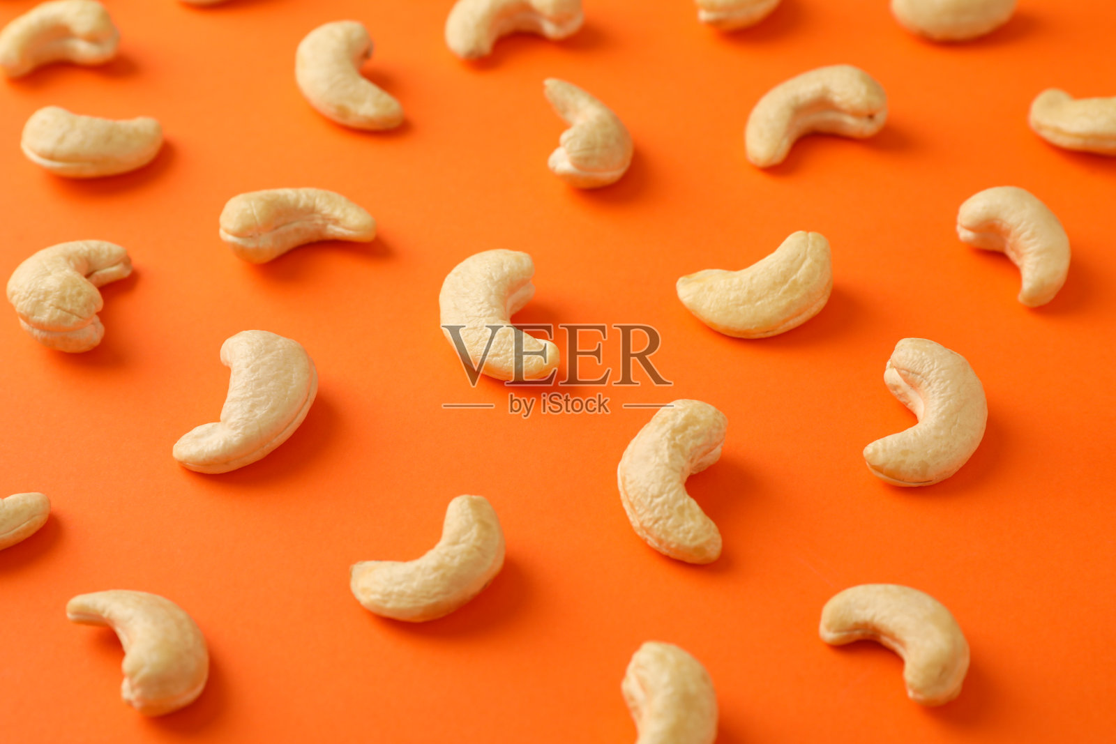 以橘色为背景,平铺腰果。维生素的食物照片摄影图片