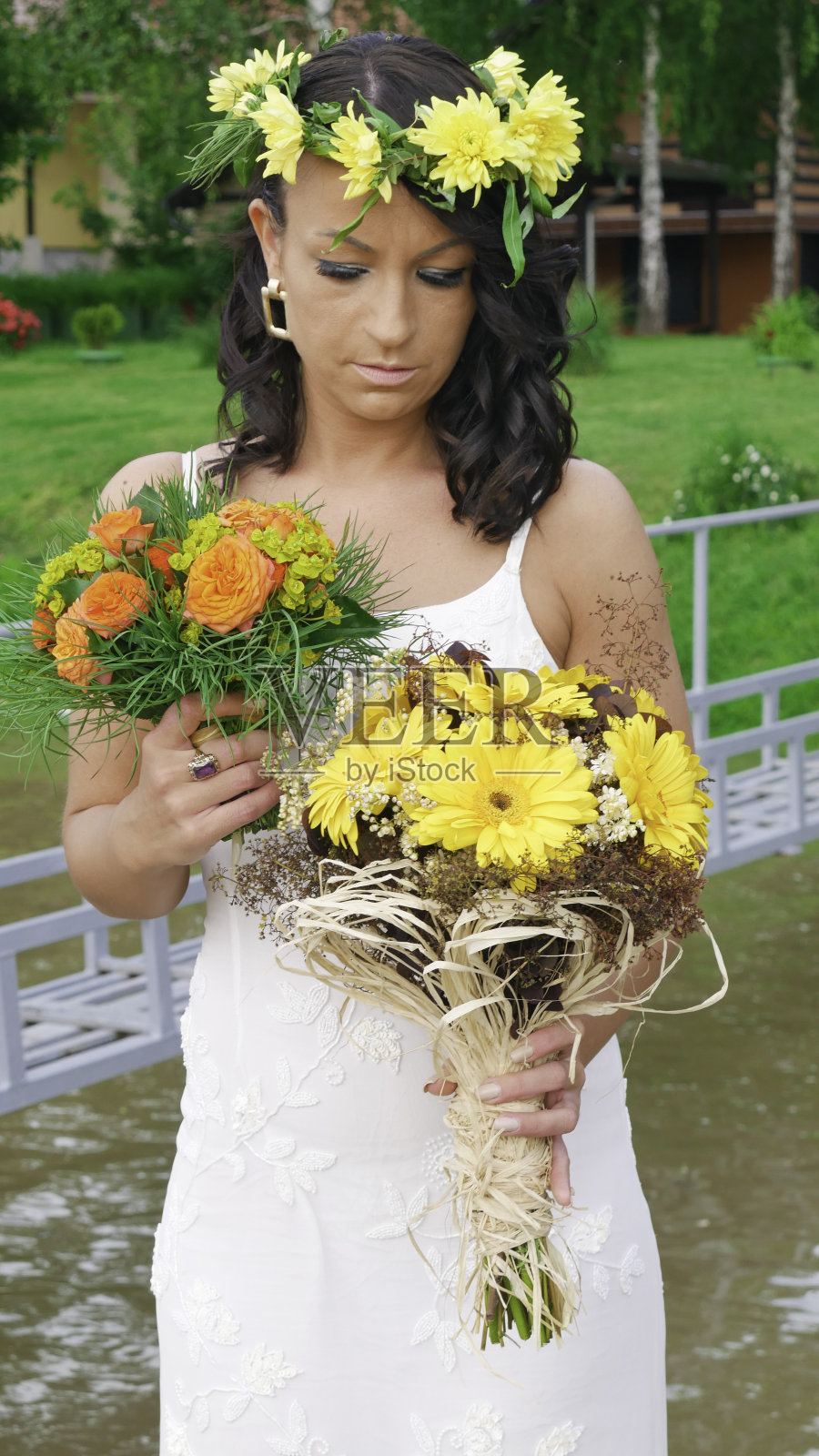 一个戴着黄花花环的新娘,手捧两束花束。照片摄影图片