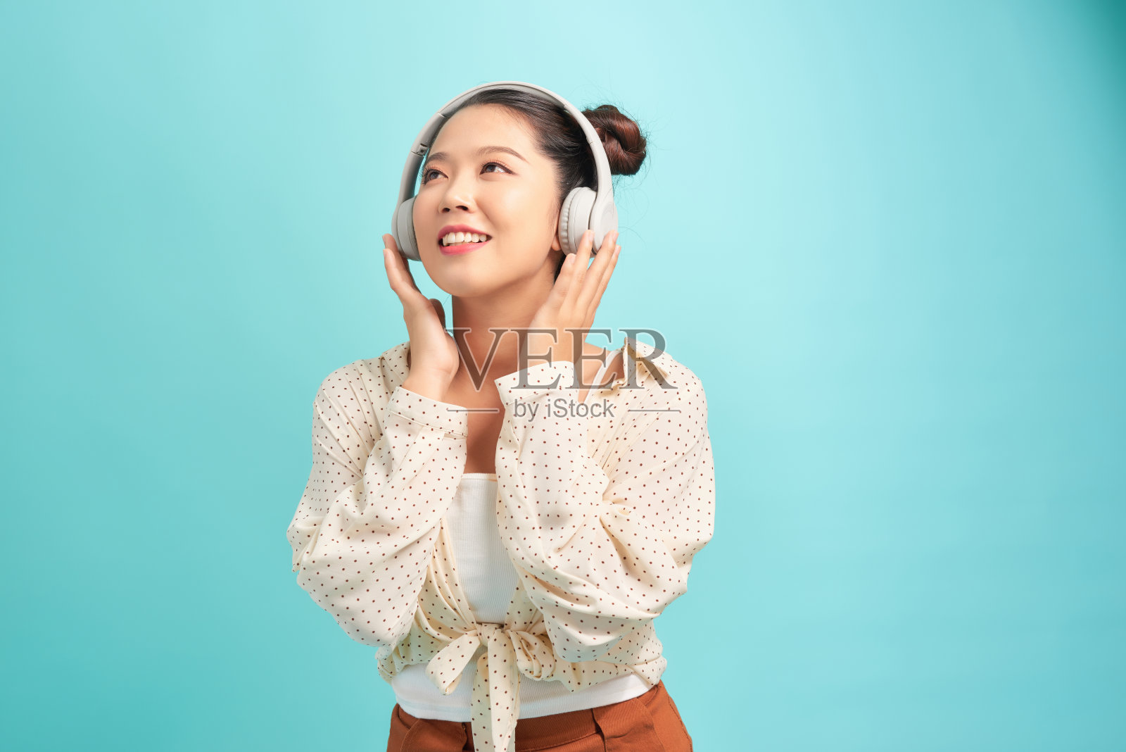 女人戴着耳机听音乐。音乐少女与蓝色共舞。背景孤立。照片摄影图片