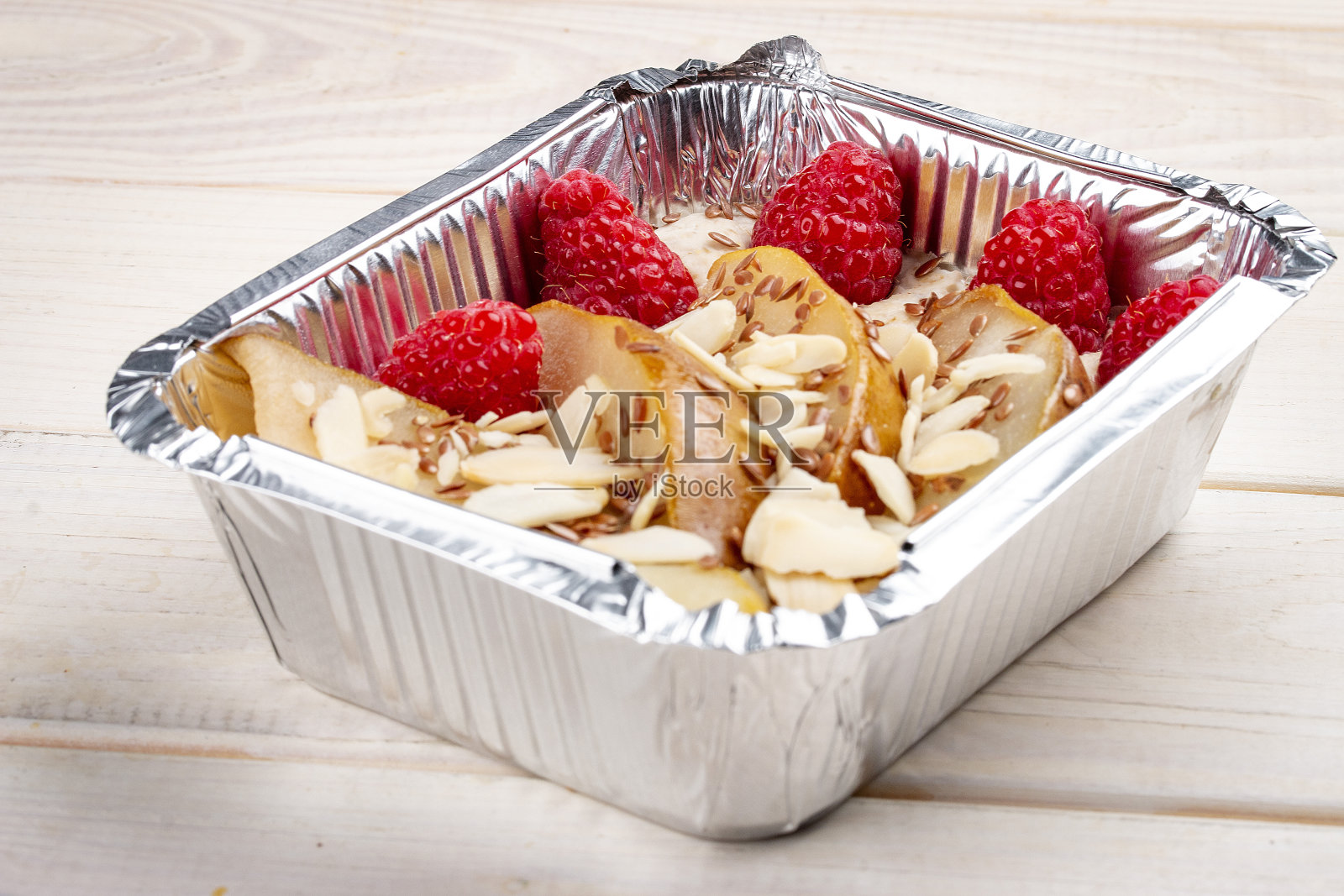 在白色的木质背景上,装有梨和覆盆子的粥。外卖。饮食和健康食品。照片摄影图片