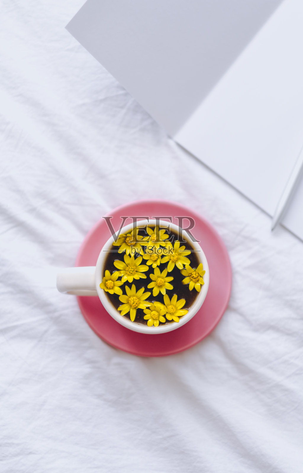 白色床上放着黄花的杯子照片摄影图片