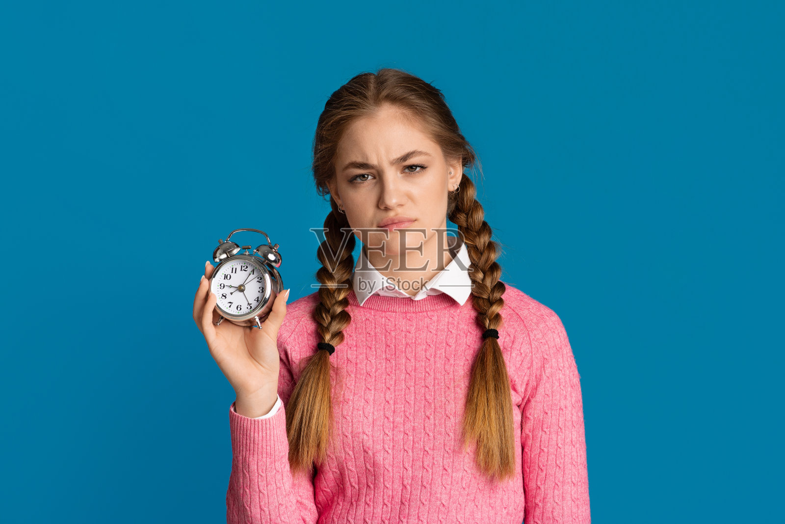 睡过头的概念。梳着辫子的疲惫少女手里拿着一个闹钟照片摄影图片