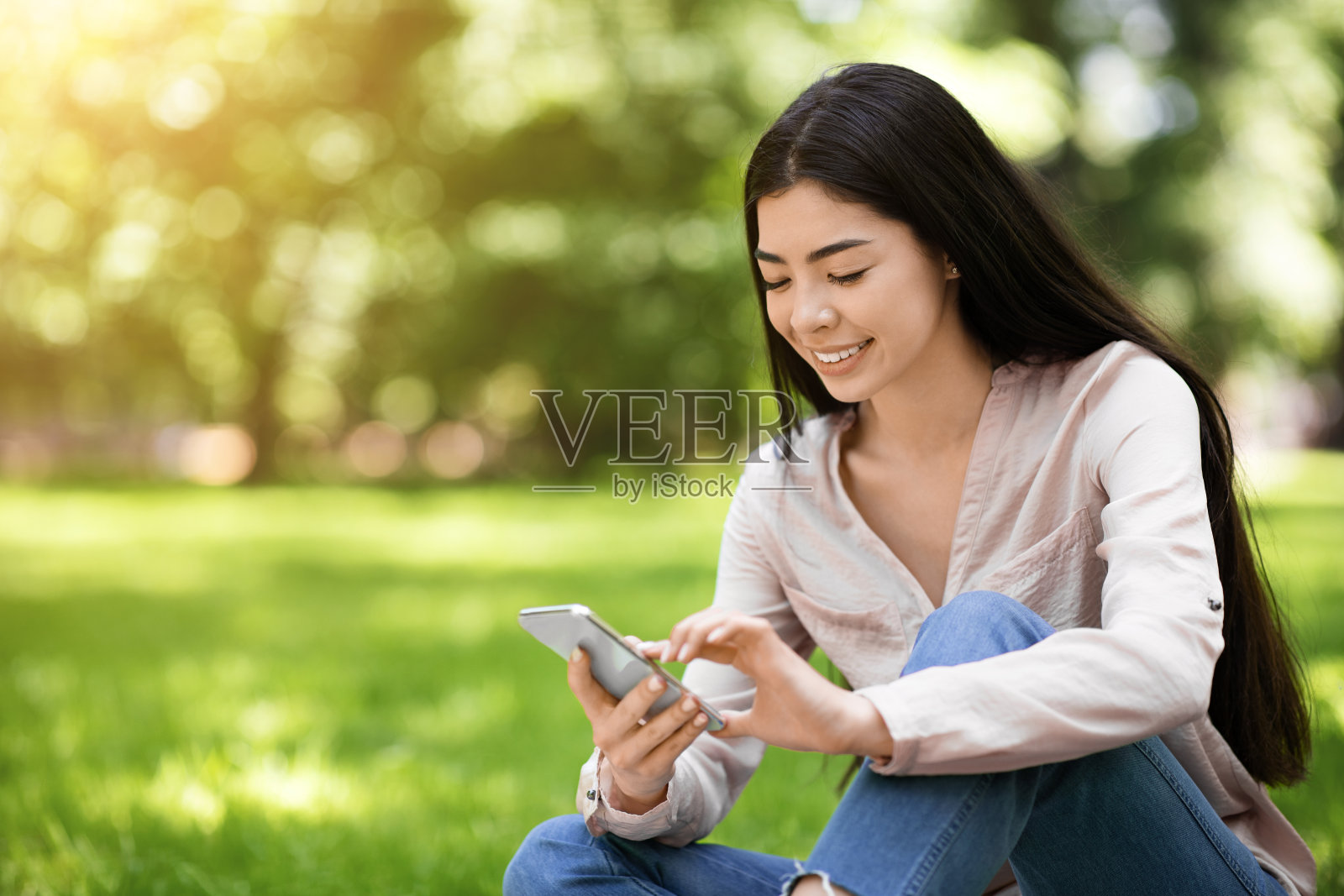 美丽的亚洲女孩在公园放松与智能手机照片摄影图片