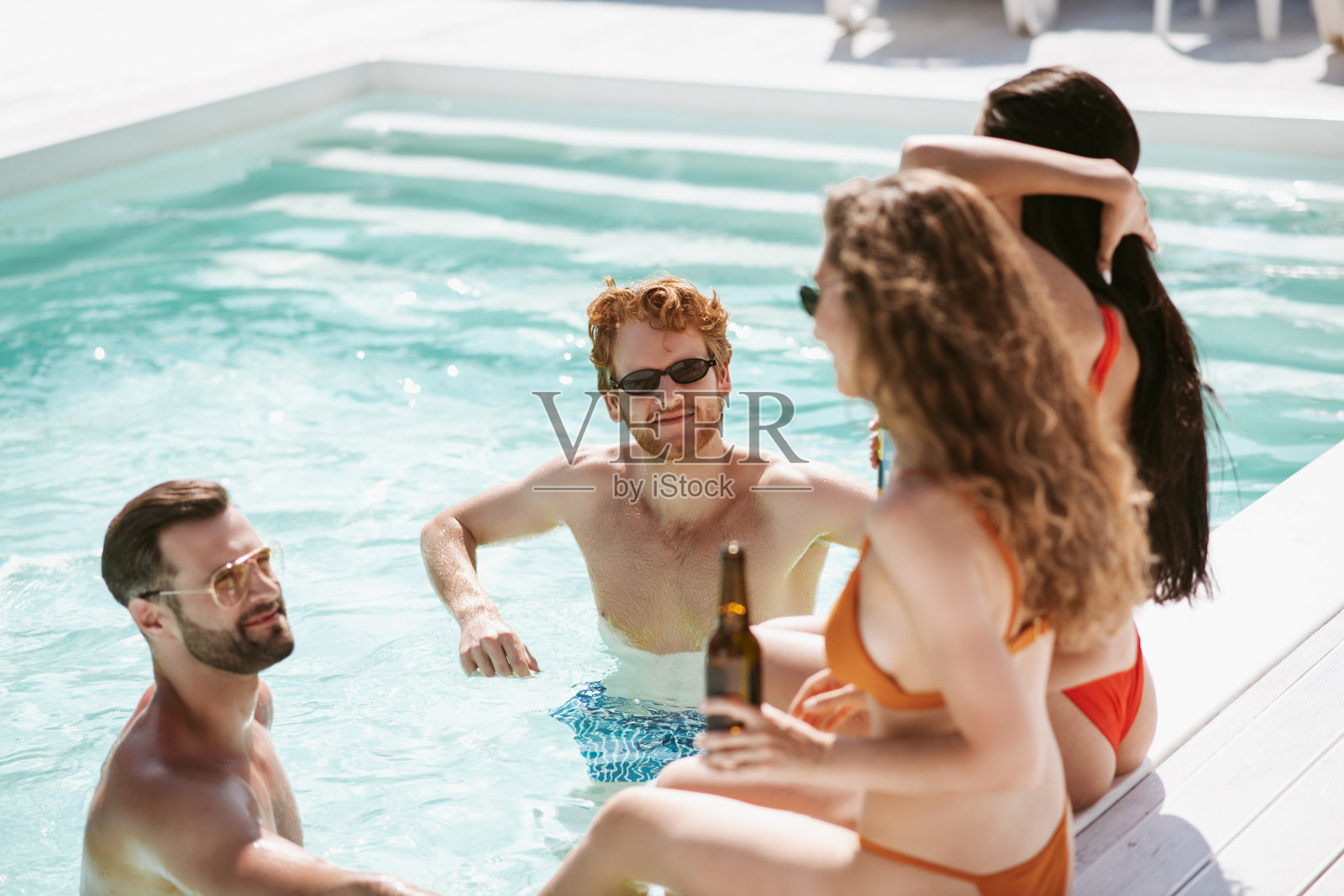 两个年轻男人在泳池里和漂亮女人聊天,感觉很挑逗照片摄影图片