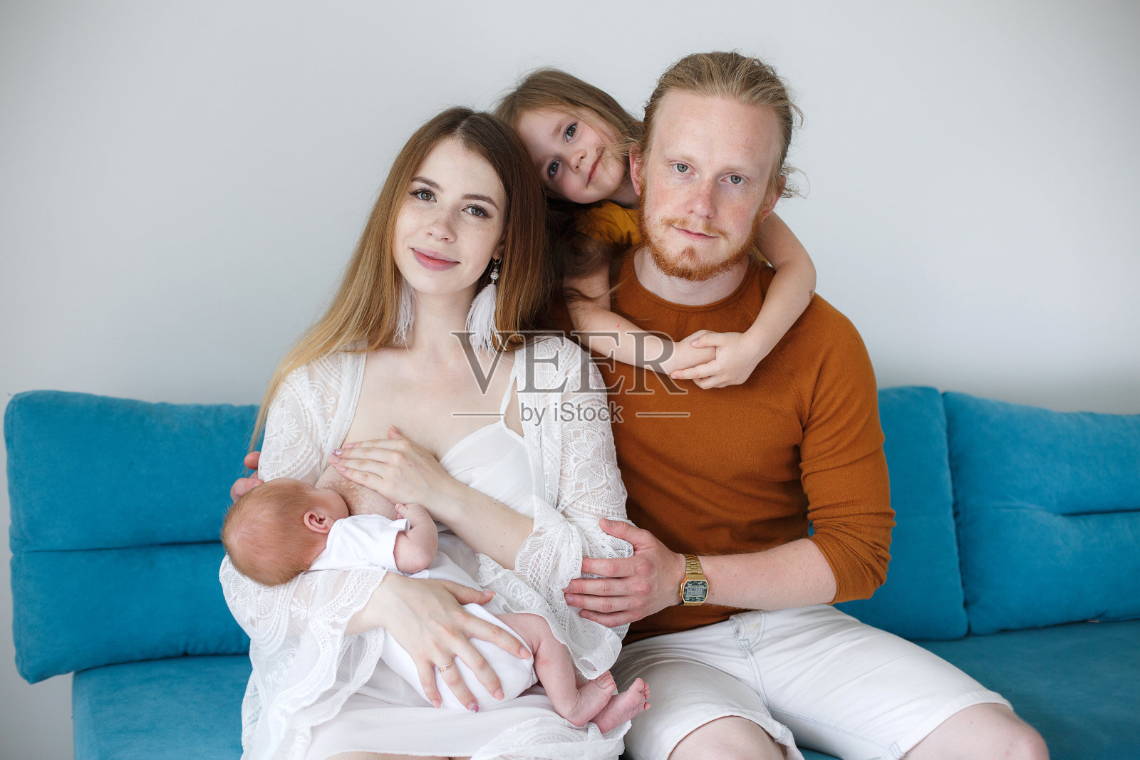 一对幸福的年轻父母抱着一个刚出生的儿子和一个十几岁的女儿在工作室的白色背景。照片摄影图片