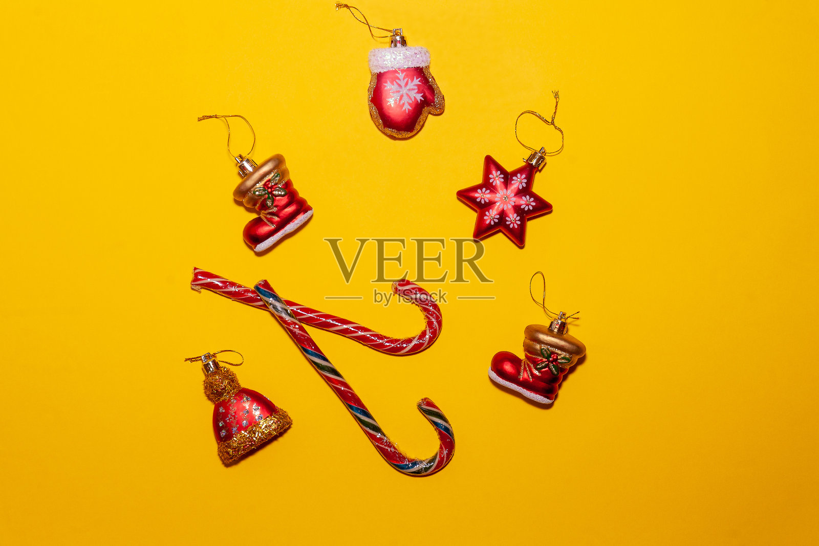 黄色背景上是棒棒糖,周围是圣诞装饰。照片摄影图片