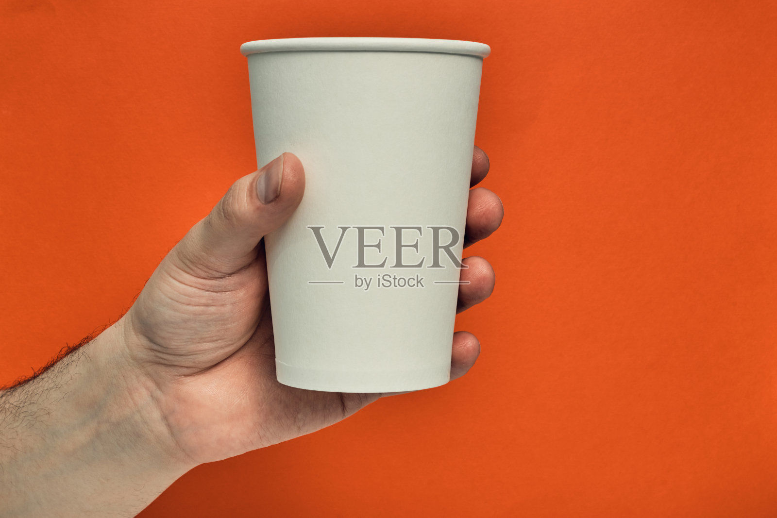 手里拿着纸杯,背景是彩色的。咖啡店里的环保材料,可降解一次性餐具。近距离照片摄影图片