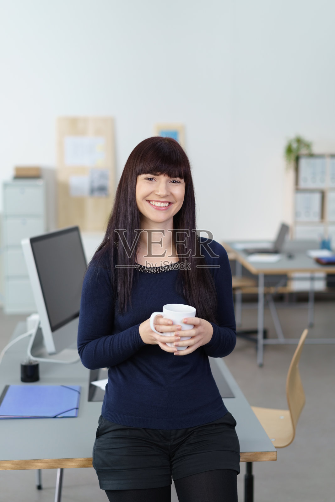 年轻微笑的女人在她的工作场所照片摄影图片