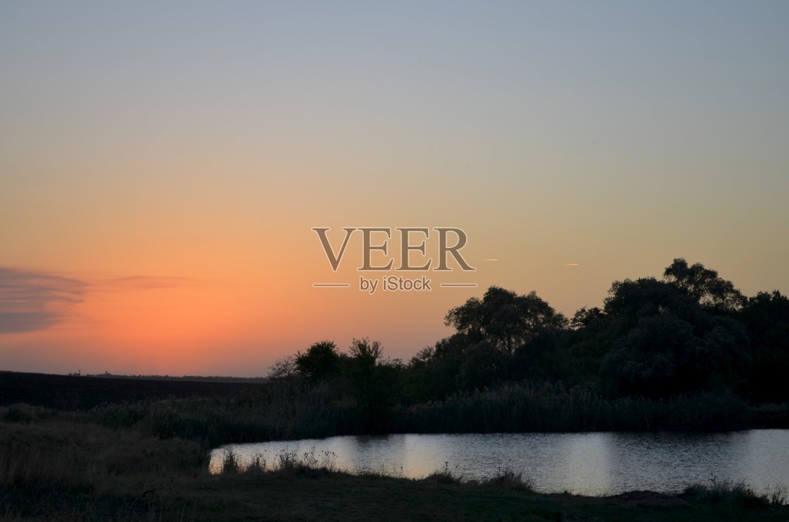 自然的景观。日落的天空和两架正在飞行的飞机在池塘的右边。照片摄影图片