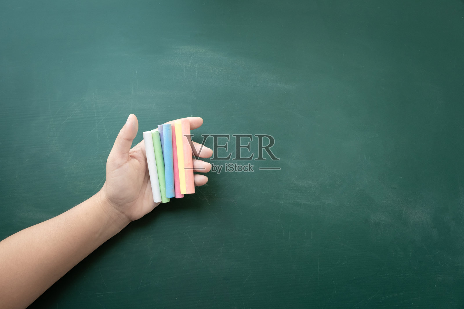 妇女的手里拿着彩色的粉笔棒作为黑板、老师和学校用品照片摄影图片
