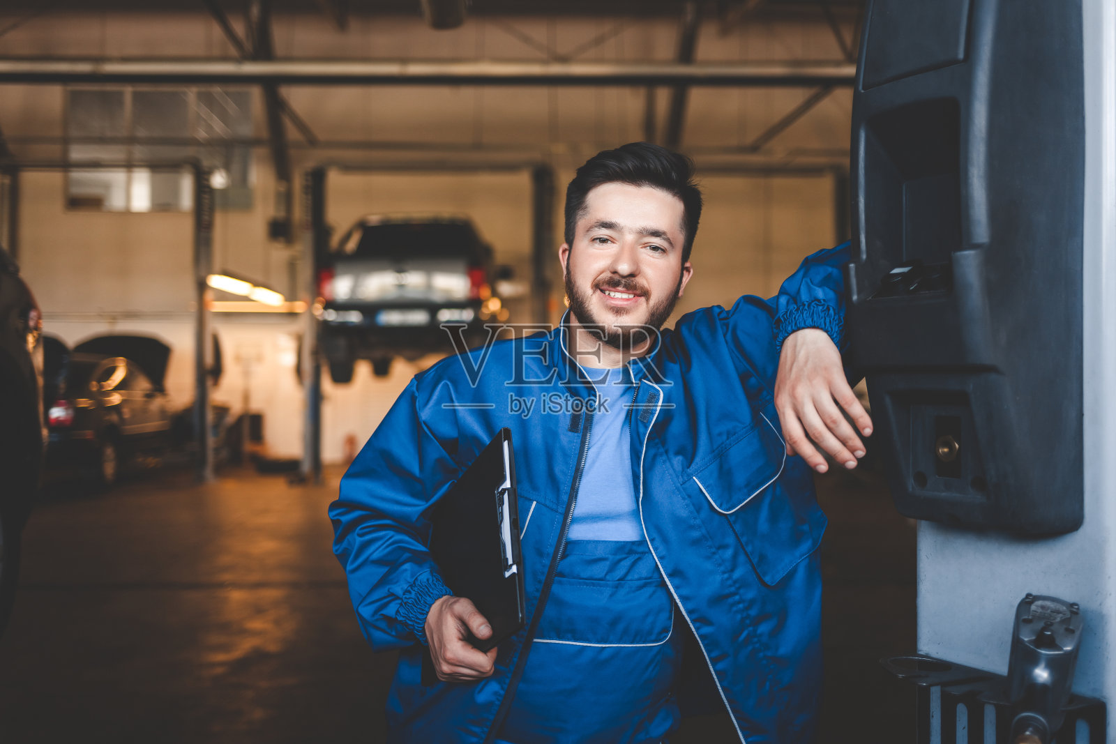 一个积极的汽车修理工在车库的肖像照片摄影图片
