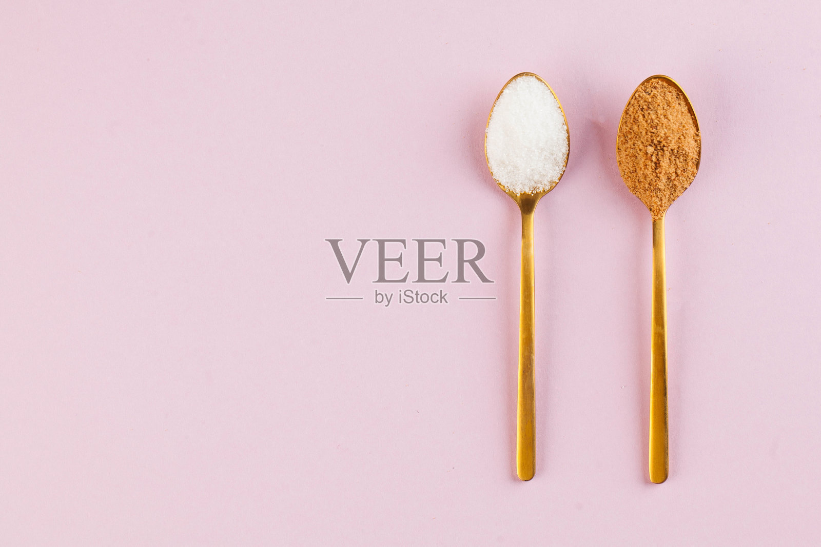 粉色背景上用金汤匙舀出椰子和精制白糖。极简主义。健康饮食。本空间照片摄影图片