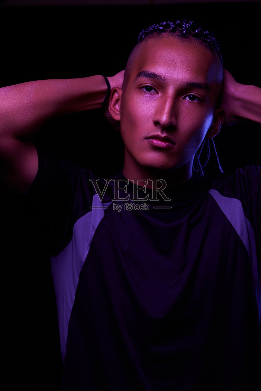 一个年轻的非洲人在工作室的肖像。时装男模特在五颜六色的霓虹灯下在黑色背景下摆姿势。艺术设计的概念。有选择性的重点照片摄影图片