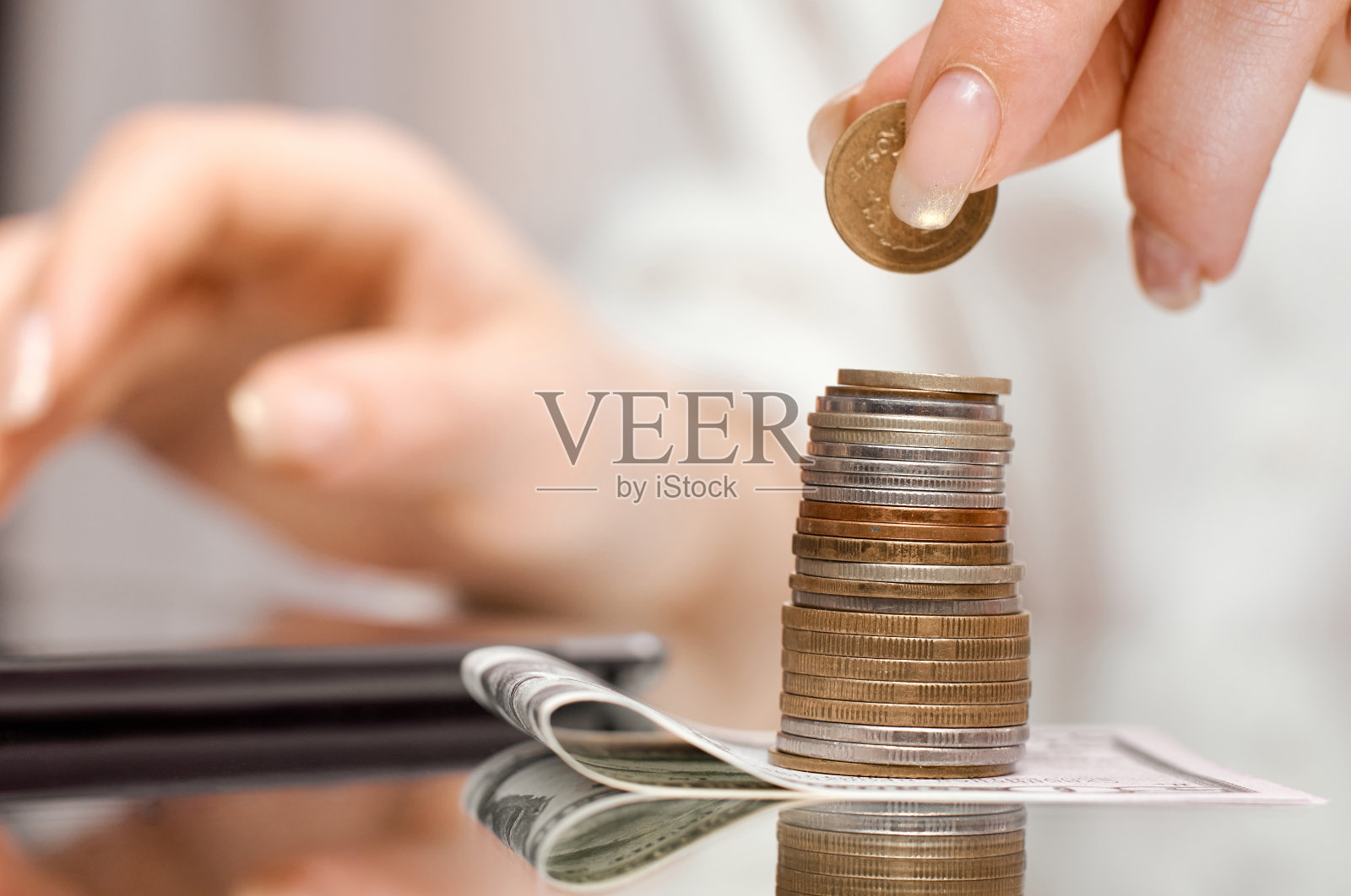 把钞票上的硬币堆在写字板旁边,女孩就在写字板上数她的收入照片摄影图片