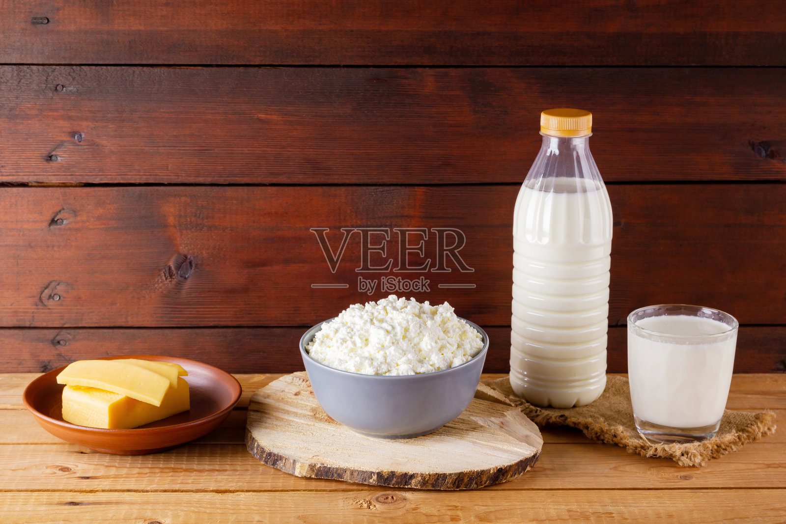 木制板上的乳制品。粗麻布上放牛奶和白软干酪。乡村风格。本空间照片摄影图片