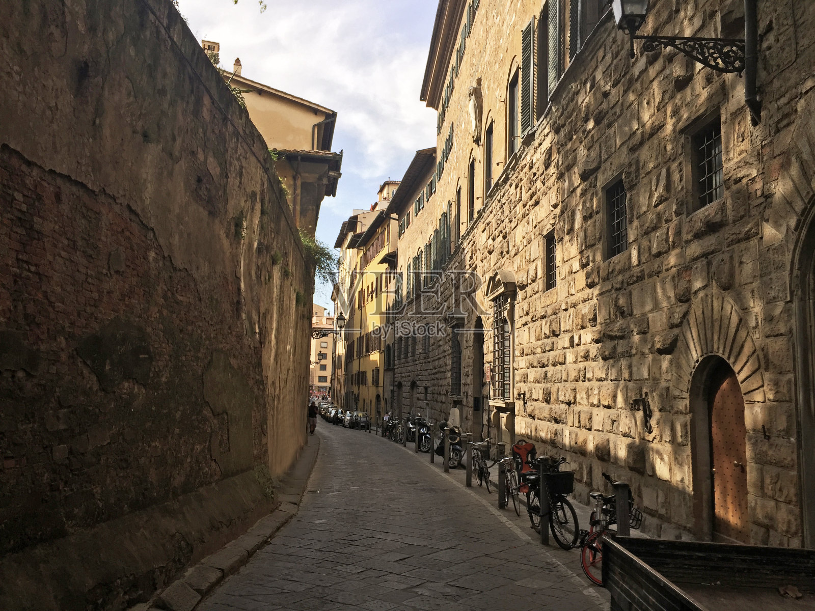 意大利佛罗伦萨狭窄的街道,有停放的自行车、摩托车和汽车照片摄影图片