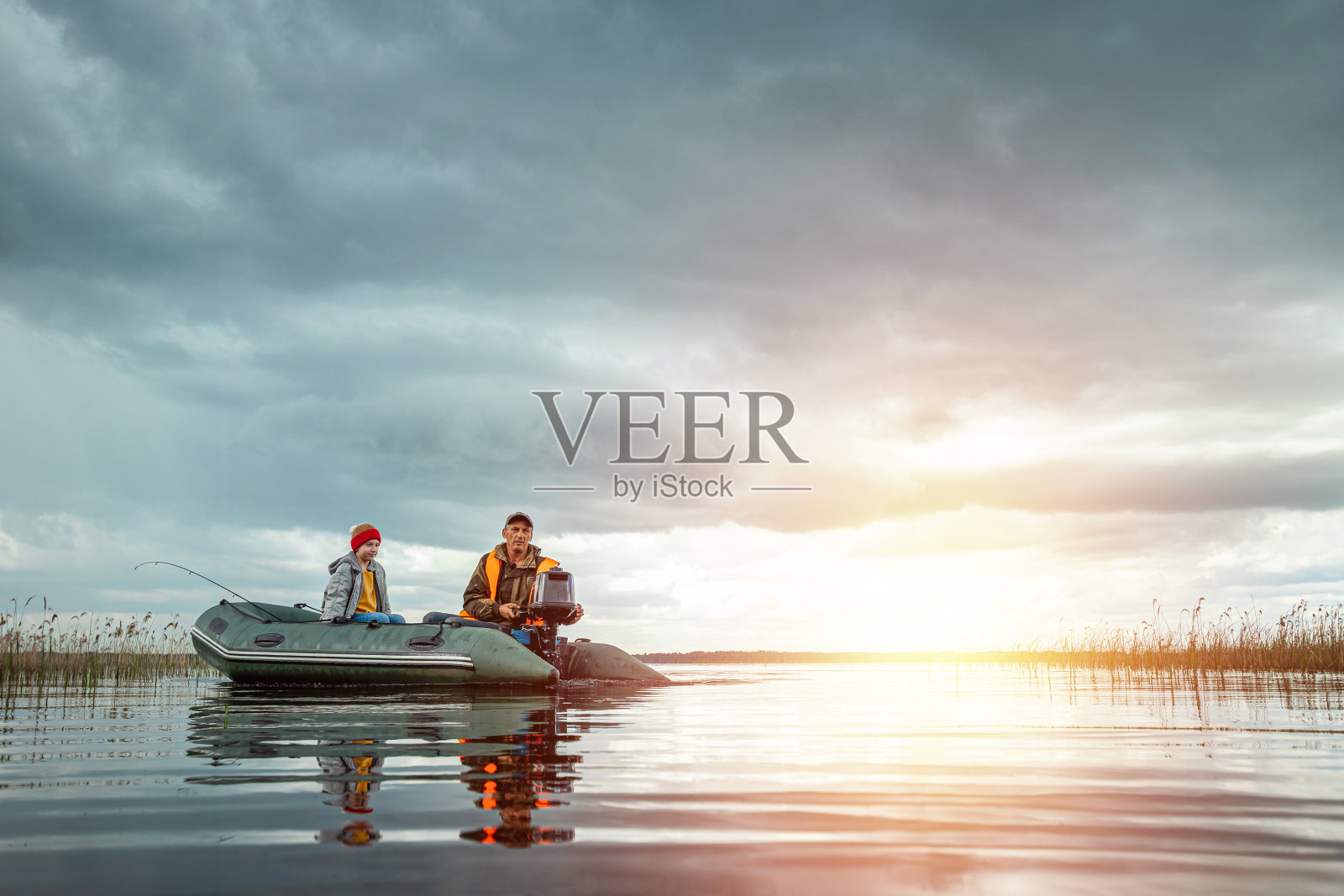 父亲和儿子在湖上乘坐摩托艇。家庭的概念,暑假,一代。副本的空间。照片摄影图片