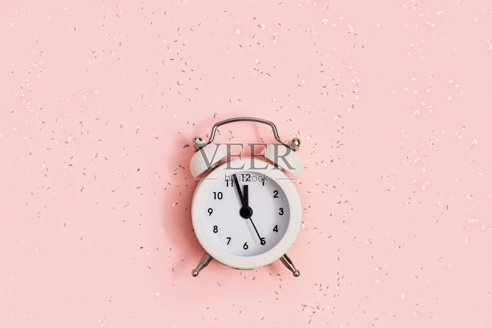 白色闹钟显示大约十二oÑ锁在粉红色的纸背景覆盖亮片与拷贝空间。新年圣诞概念。平的。前视图。照片摄影图片