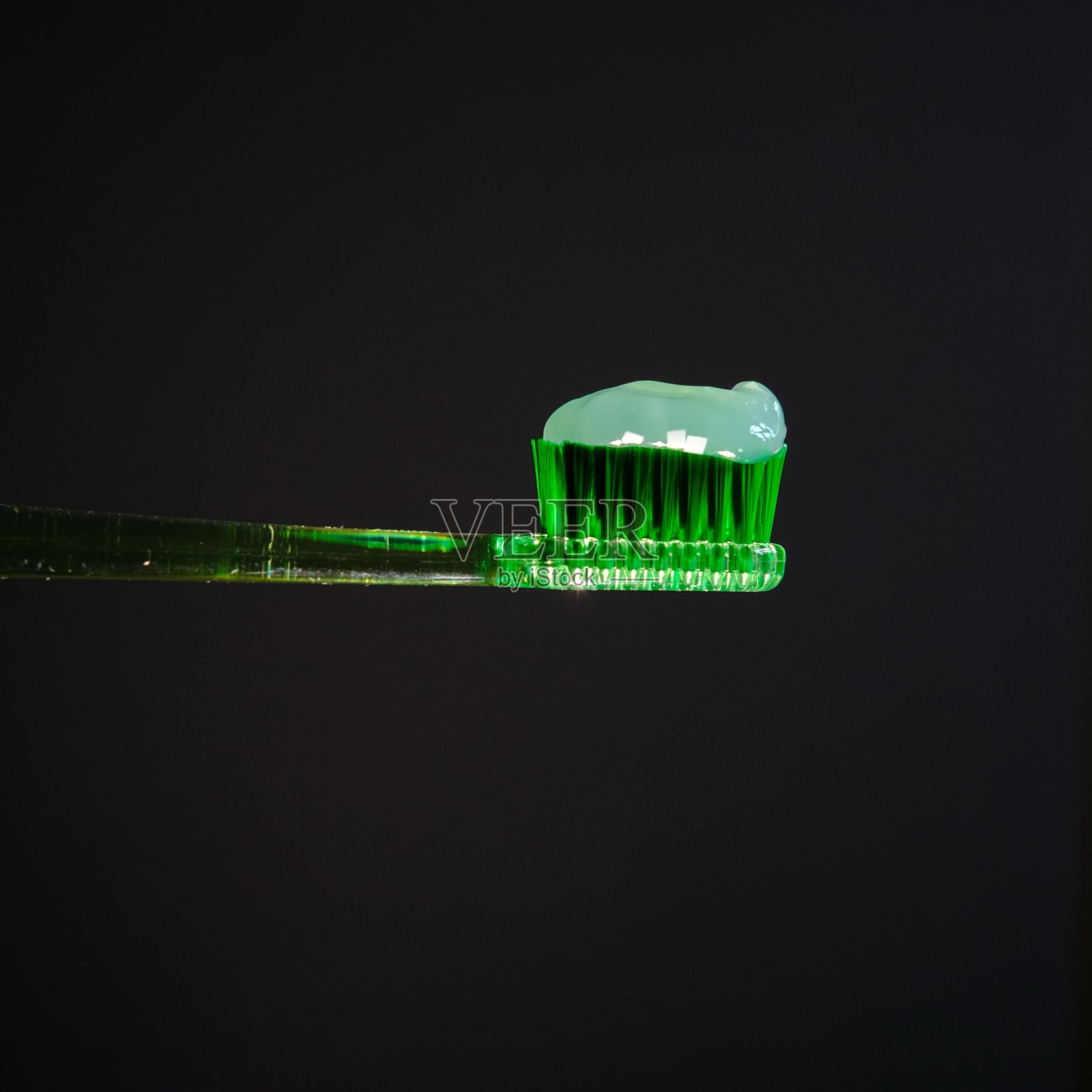 绿色透明牙膏,绿色牙刷,黑色背景照片摄影图片