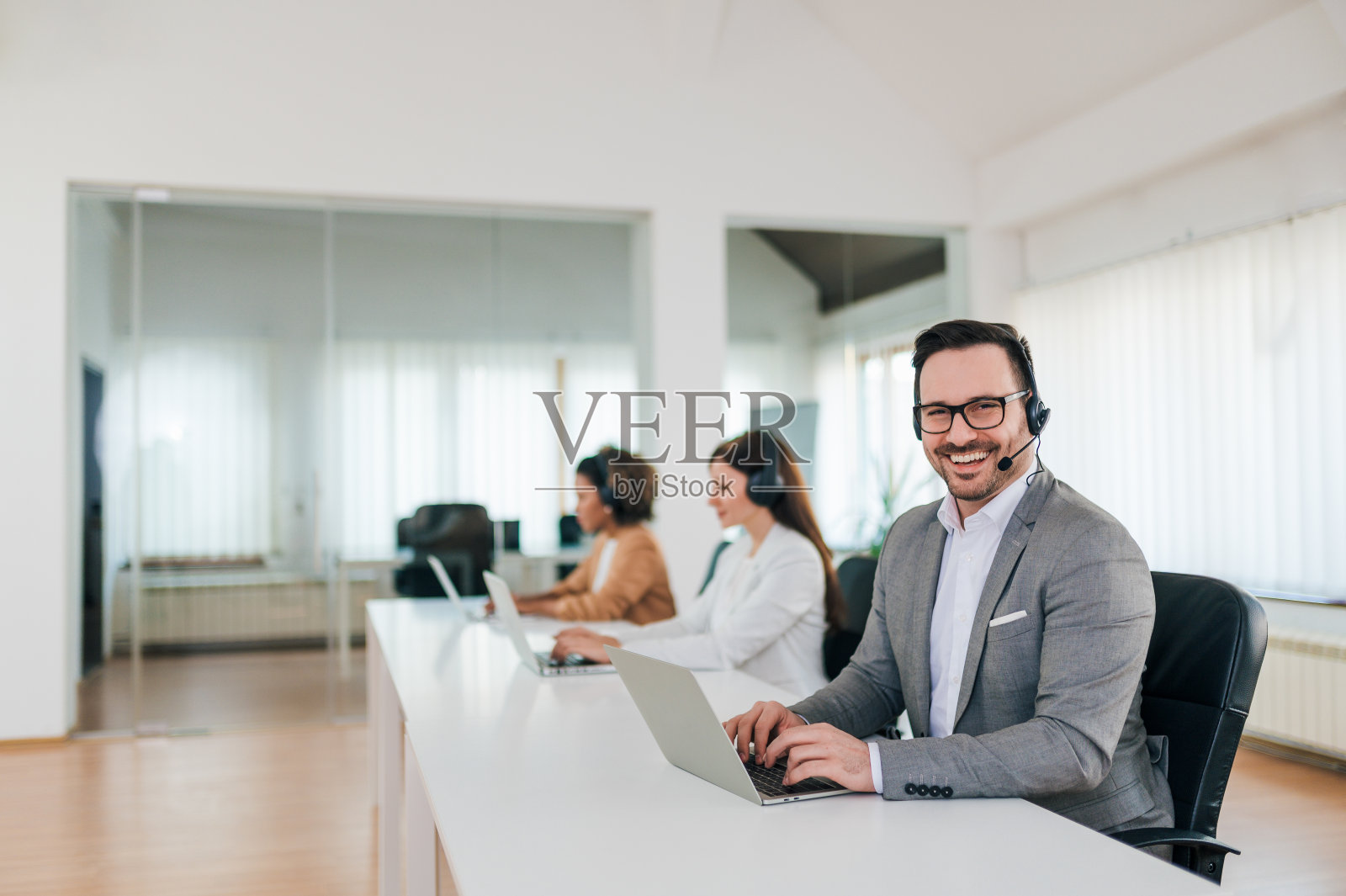 一个愉快的接线员在明亮的办公室里的肖像。照片摄影图片