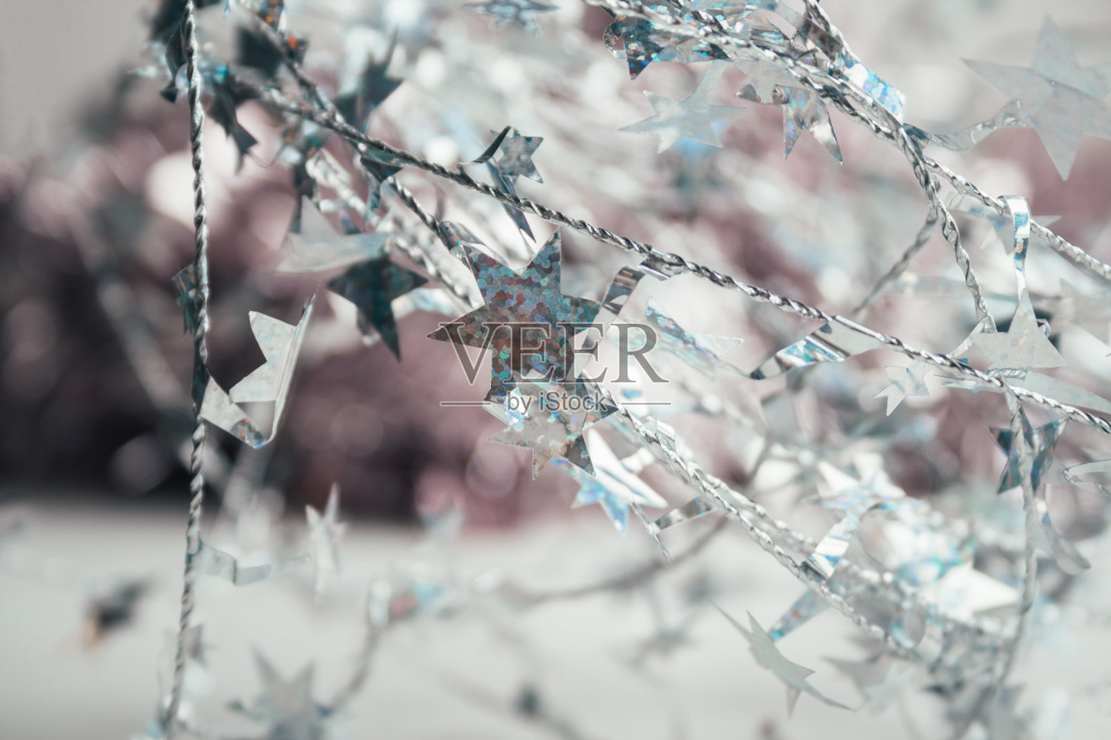 美丽的圣诞背景,银色扭曲的电线与星星在模糊的淡粉色。神奇的新年心情。装饰家庭或圣诞树。选择软焦点照片摄影图片