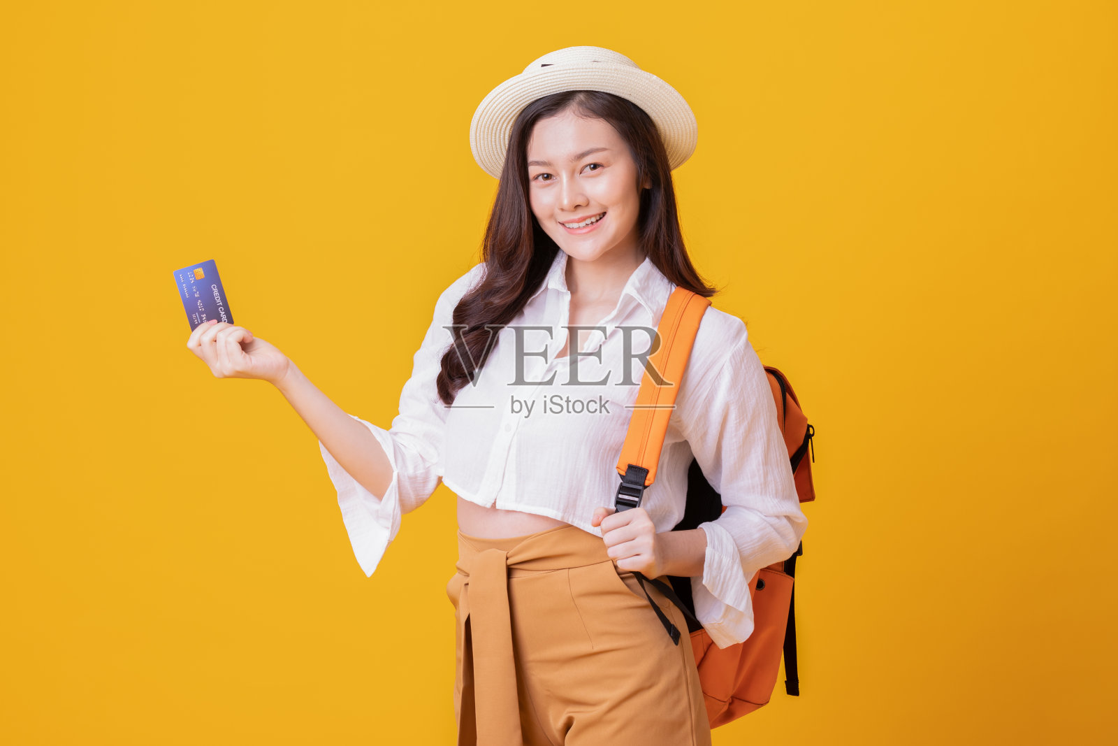 快乐的旅行者旅游亚洲女人与旅行袋和夏天的帽子准备旅行和持有信用卡,孤立在黄色的背景,旅游和度假的概念照片摄影图片