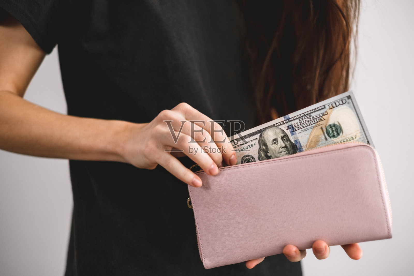 一名年轻女子从钱包里拿出了美元钞票。近距离照片摄影图片