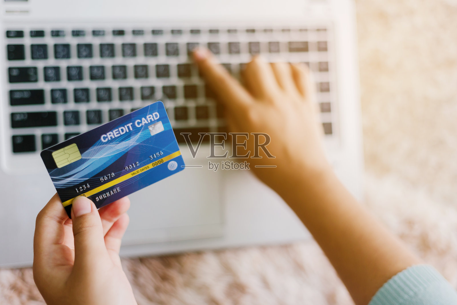 手握信用卡,使用笔记本电脑的女人。网上购物的概念照片摄影图片