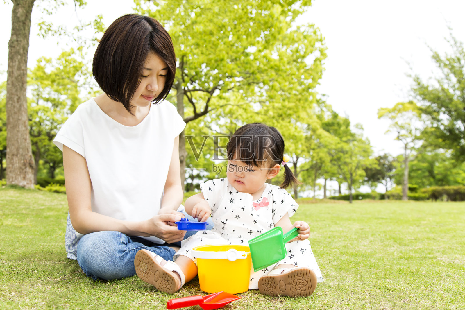 小女孩和妈妈在公园里玩耍,背景是新鲜的绿树照片摄影图片