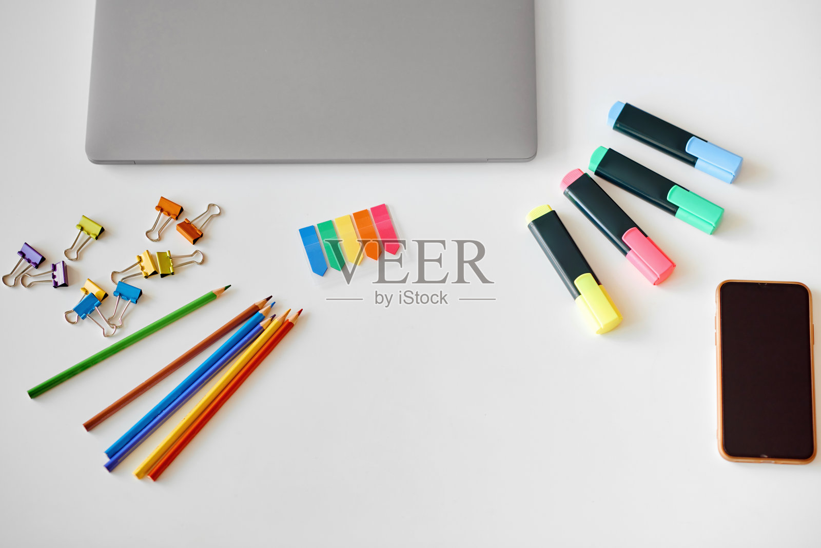 桌子上有各种颜色的文具、笔记本电脑和电话照片摄影图片