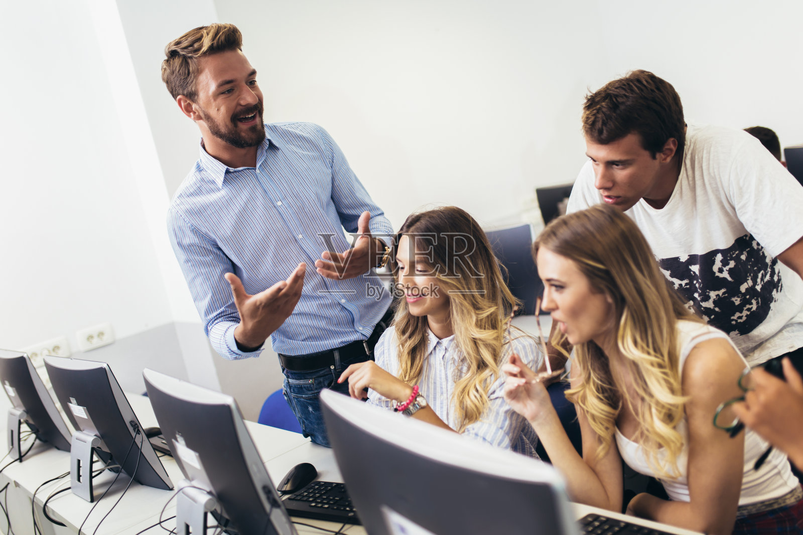 在计算机课上帮助学生的老师照片摄影图片