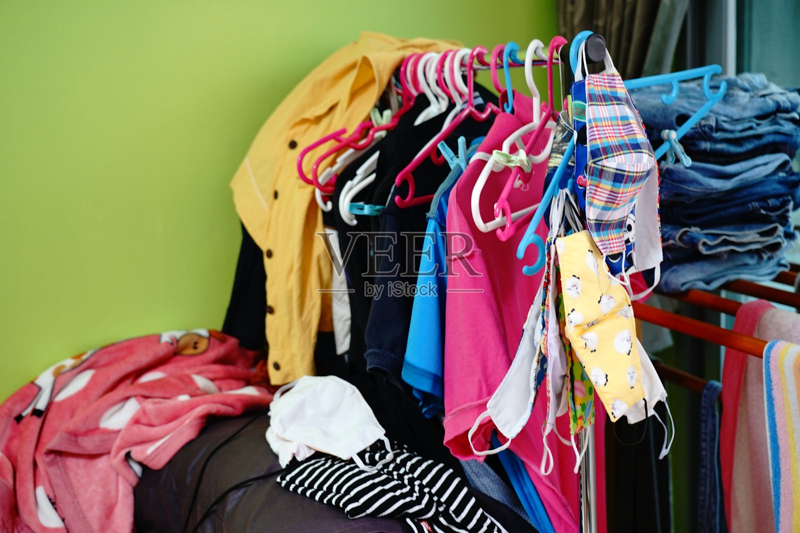 凌乱的衣服散落在沙发上,洗好的衣服挂着。照片摄影图片