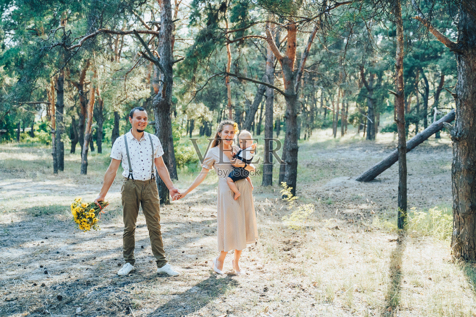 年轻快乐的家庭在森林里散步。父母抱着孩子玩得很开心。他们在一起很快乐。互相微笑,向前看照片摄影图片