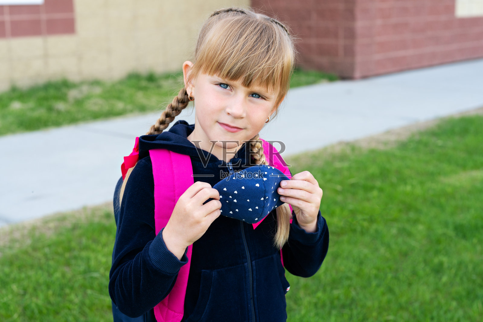 年轻的学生白人女孩拿着保护棉面具上学。回到学校,重新开张,新的生活照片摄影图片