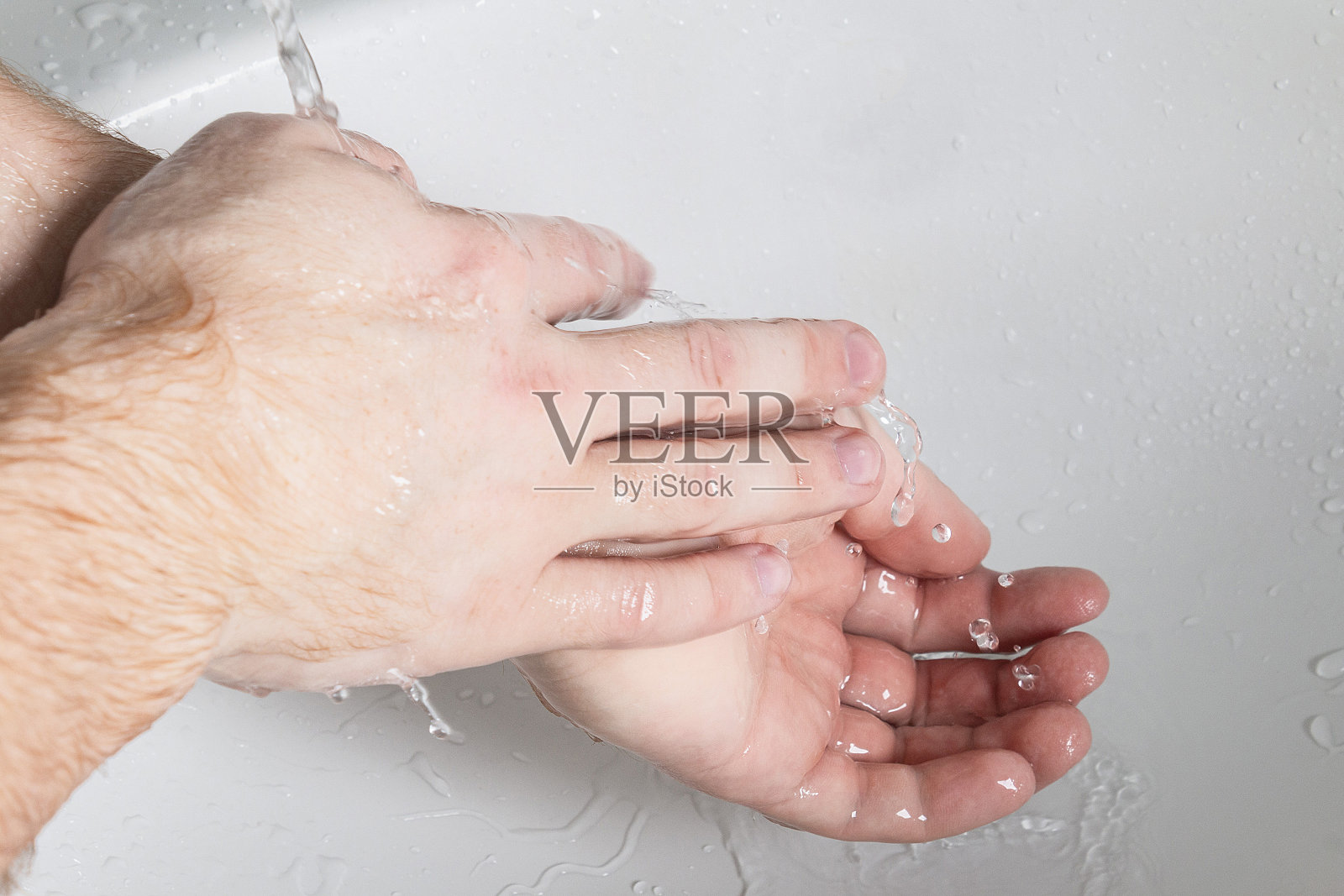 男人在水龙头下用肥皂洗手。卫生概念手的细节。照片摄影图片