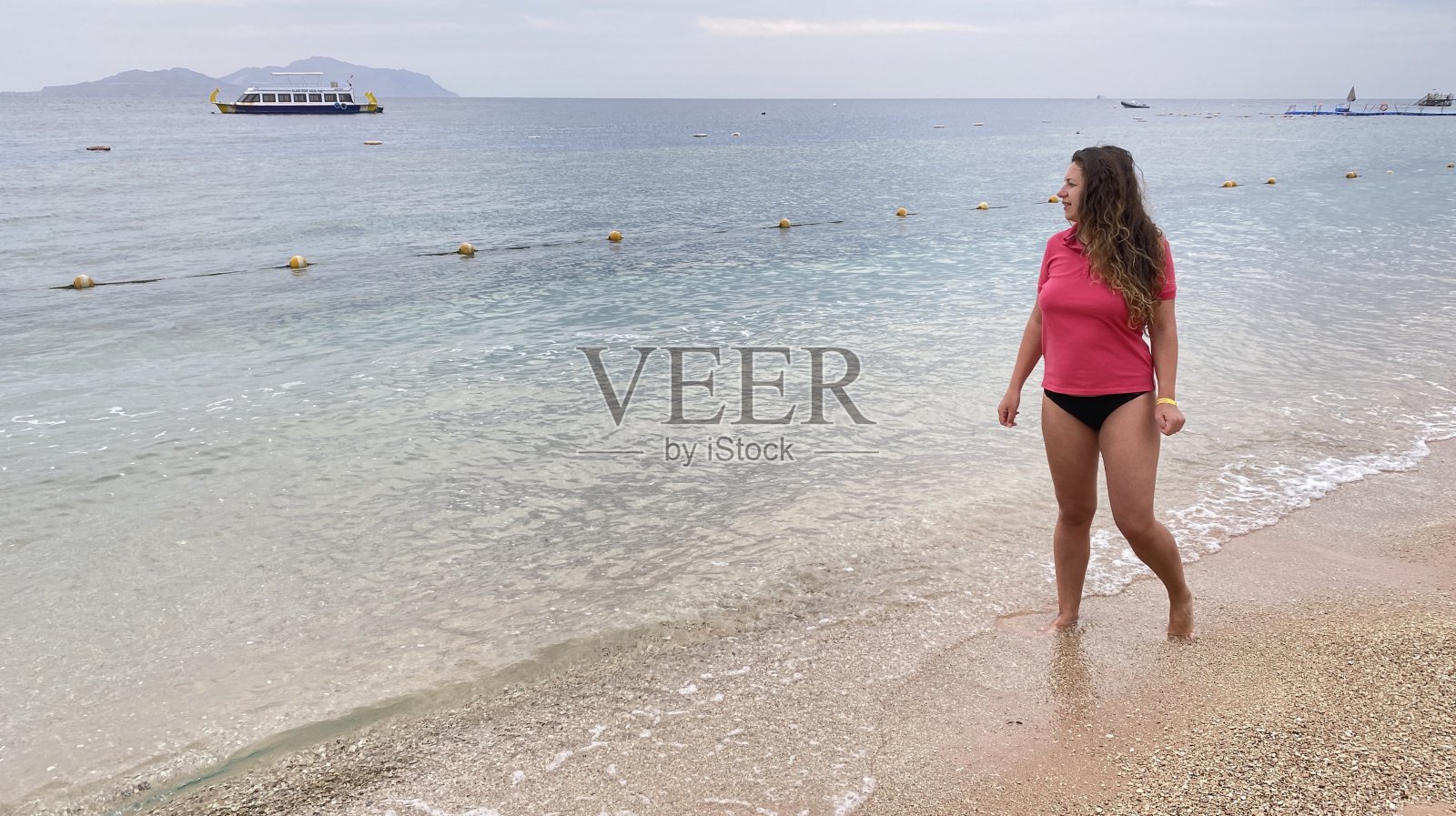 一位年轻女子早晨沿着海滩散步。照片摄影图片