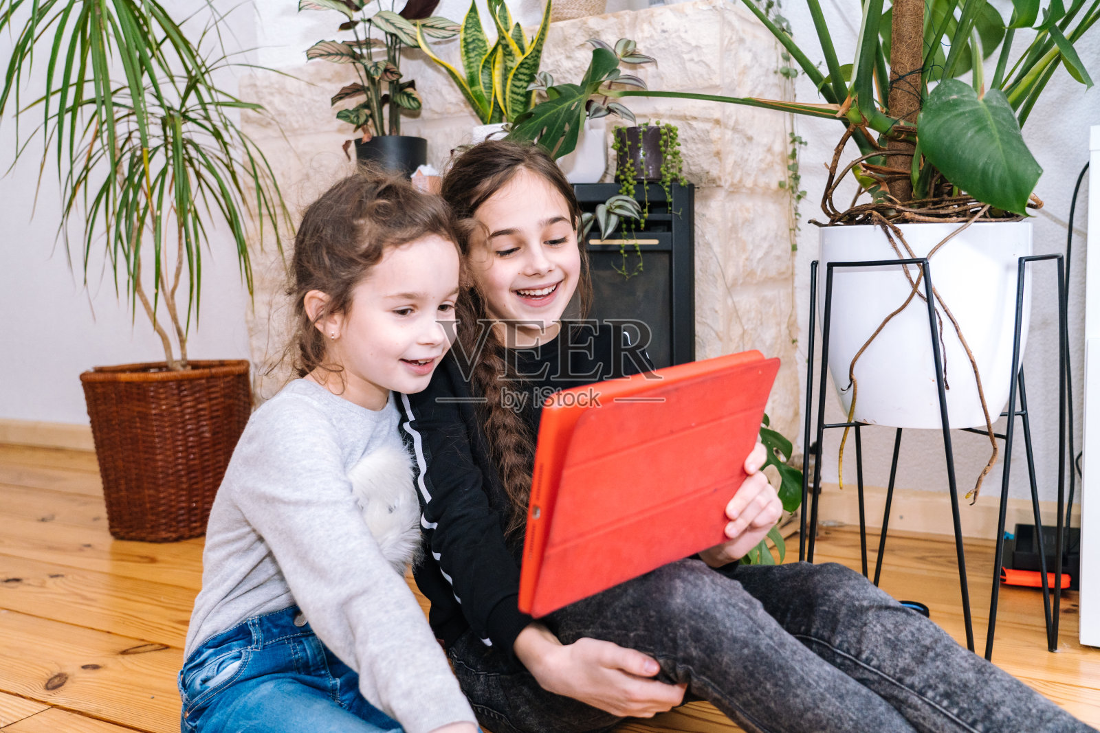 带着孩子坐在家里,拿着视频电话的女人。家人使用智能手机与朋友或家人视频通话。人们通过看视频的摄像机和挥手致意的手交流。照片摄影图片