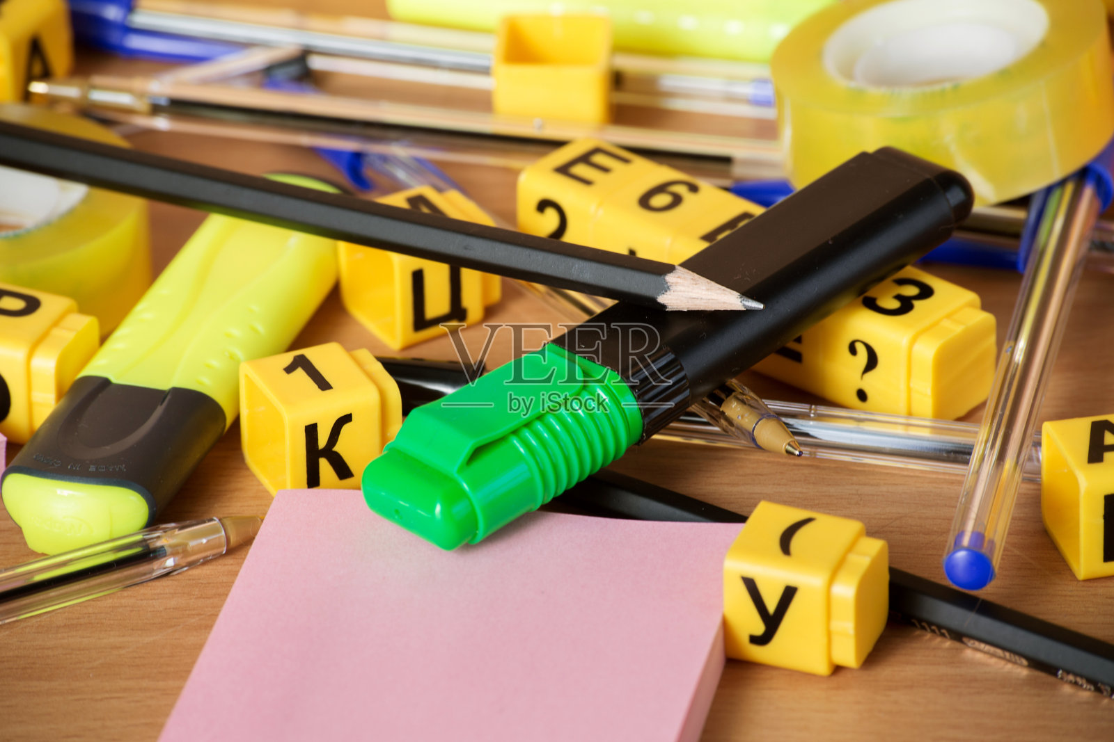 钢笔,铅笔,文本分隔器,磁带,回形针,和一个装有字母和数字的工具箱放在木桌上。学校准备和办公用品照片摄影图片