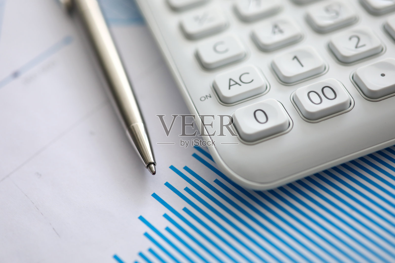 白色计算器和银色钢笔躺在纸图表照片摄影图片