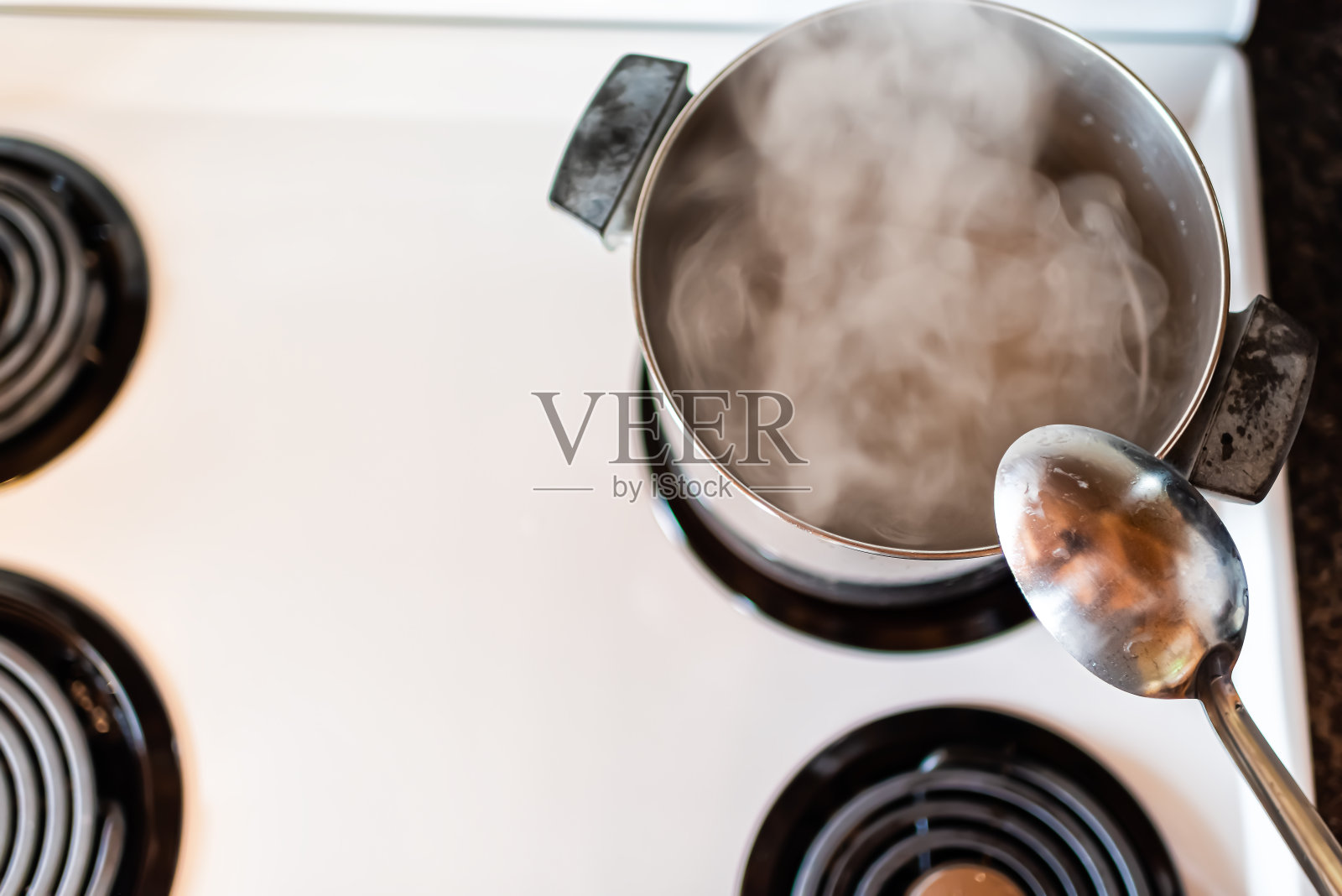 特写的复古老式灶台顶部与白色的平顶视图和不锈钢锅和蒸汽烹饪在复古厨房与勺子照片摄影图片