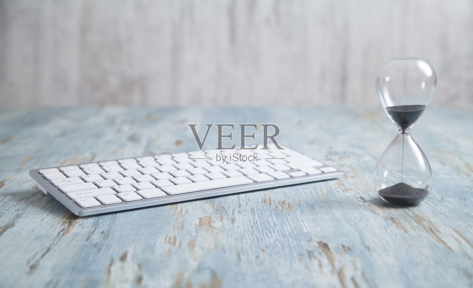 桌上放着一个电脑键盘的沙漏。照片摄影图片