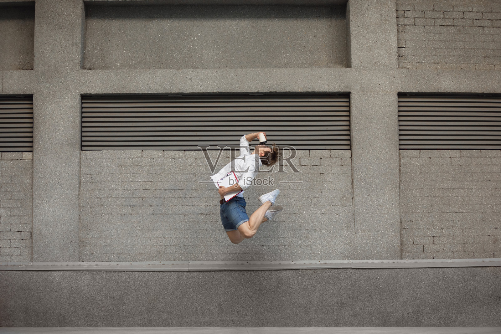 年轻人在楼前跳跃,在奔跑中跳得很高照片摄影图片