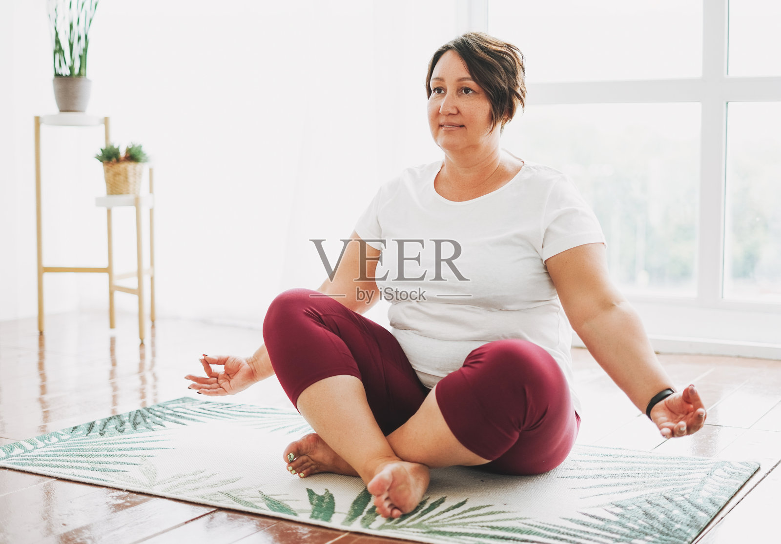 成年迷人的黑发女人加上大小的身体积极练习瑜伽在明亮的工作室照片摄影图片