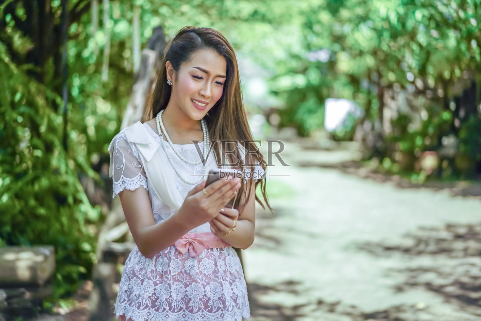 穿着泰国传统服饰的漂亮女人在用智能手机照片摄影图片